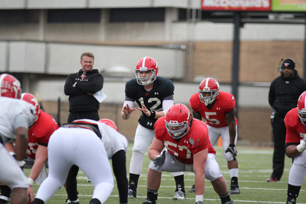 Quarterback Kurt Hess (12) prepares to take the snap as head coach Eric Wolford (back left) looks on during Saturday’s scrimmage. The Penguins open their season Thursday at 7:30 p.m. at Stambaugh Stadium against the University of Dayton. Photo by Dustin Livesay/The Jambar. 