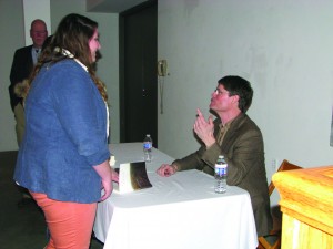 Bruce Mills explains to a YSU student the dynamics behind his memoir as he signs her book.