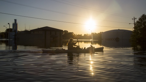 Buckley Miller paddles a canoe past a flooded water treatment plant in downtown Lumberton, N.C., after Hurricane Matthew caused downed trees, power outages and massive flooding along the Lumber River, on Tuesday, Oct. 11, 2016. (Travis Long/Raleigh News & Observer/TNS)
